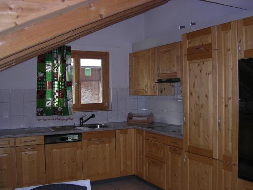 克洛斯特斯Gotschnablick的厨房配有木制橱柜、水槽和窗户。