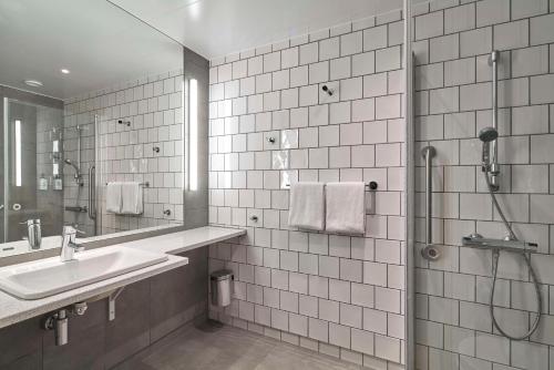哥德堡Scandic Göteborg Central的白色瓷砖浴室设有水槽和淋浴