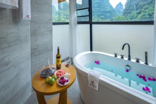 阳朔Qingshan Yuandai Resort Hotel Yangshuo Yulong River National Tourism Resort Store的带浴缸和酒杯桌子的浴室