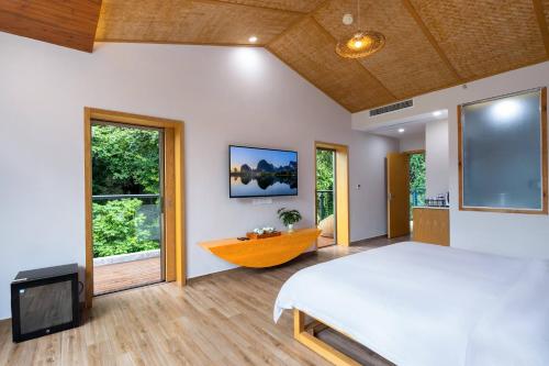 阳朔Qingshan Yuandai Resort Hotel Yangshuo Yulong River National Tourism Resort Store的一间卧室配有一张大床和电视