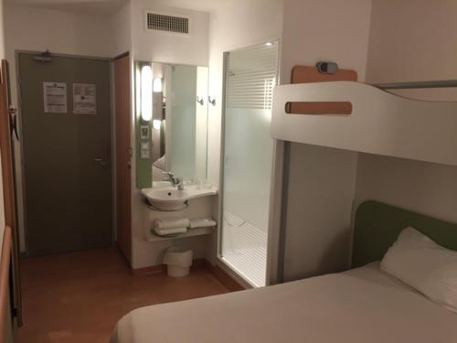 多维尔多维尔宜必思快捷酒店的一间卧室配有一张床,浴室设有水槽