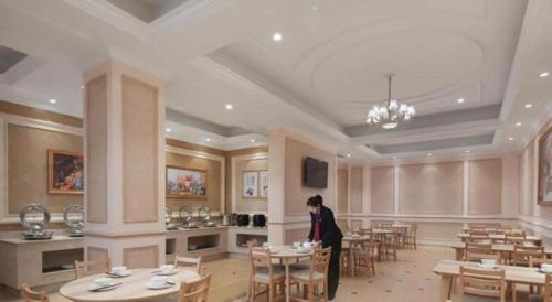 溧水Vienna Hotel Nanjing Lishui Development Zone Jichang Road的站在带桌椅的房间的妇女