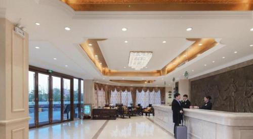 溧水Vienna Hotel Nanjing Lishui Development Zone Jichang Road的两人站在酒店大堂的酒吧