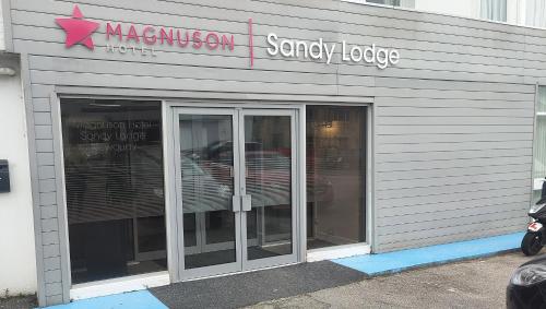 纽基Magnuson Hotel Sandy Lodge Newquay的一间商店,上面有两扇玻璃门和标志