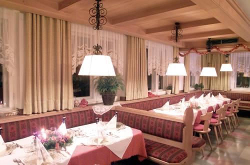 安泰塞尔瓦·迪·梅佐Hotel Bruggerwirt的用餐室配有桌椅和吊灯。