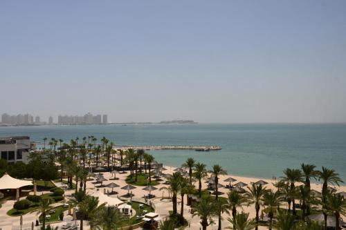 多哈InterContinental Doha Beach & Spa, an IHG Hotel的享有棕榈树海滩和大海的景色