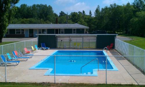 MiddletonMiddleton Motel & Suites的围栏后面的游泳池,周围设有椅子