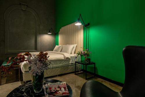 胡志明市HOTEL le JARDIN SECRET saigon的绿色的客房设有一张床和绿色的墙壁