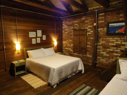 Ana RechHospedaria Rio do Vento的一间卧室设有一张床和砖墙