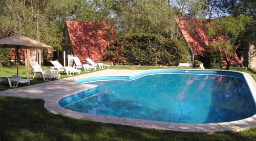 圣罗莎卡拉穆奇塔县La Campiña Cabañas的蓝色游泳池配有椅子和遮阳伞
