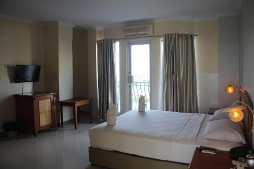 美娜多西里伯斯酒店的一间卧室设有一张大床和一个窗户。
