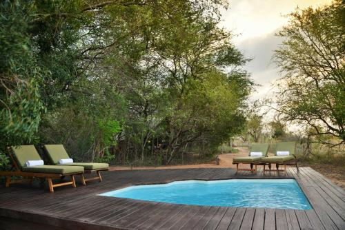 斯库库扎丛林漫步之旅酒店的木制甲板上的游泳池,配有2把躺椅