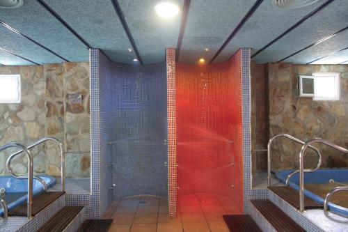 CarmonitaHotel Balneario Fuentes del Trampal的浴室设有两个水槽和红色玻璃淋浴间。