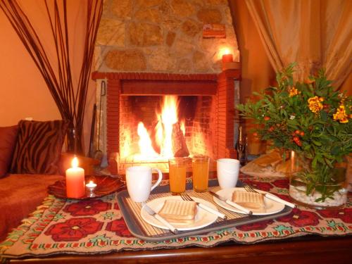 卡托卡拉库林斯Theasis suites-Ορεινή Φιλοξενία的壁炉前的餐桌,包括食物和蜡烛
