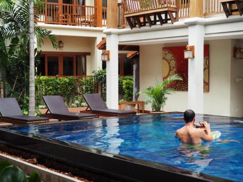 清迈荣颂歌酒店的坐在酒店游泳池里的男人