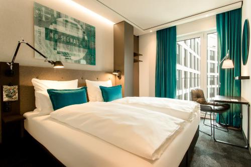 科隆Motel One Köln-Messe的卧室配有带蓝色枕头的大型白色床