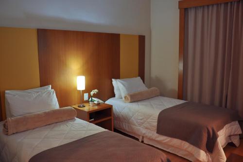 雷森迪Cegil Hotel Boulevard的酒店客房设有两张床和一张带台灯的桌子。