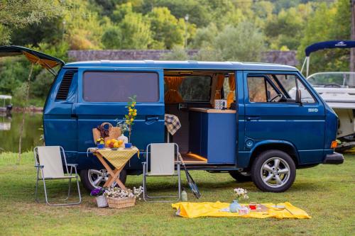 采蒂涅Vanlife Montenegro Camper Van and 2 Bikes的一辆蓝色的面包车停在田野里,里面配有桌椅