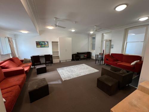 珀斯Wallaby Backpackers Hostel Perth - note - Valid passport required to check in -的客厅配有红色沙发和钢琴