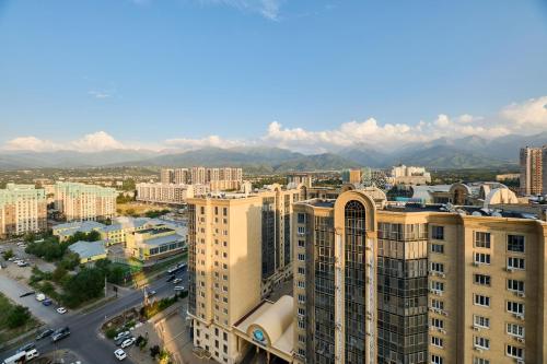 阿拉木图Five Business-class rooms in R-house near Mega Center Almaty的城市的空中景观,背景是群山