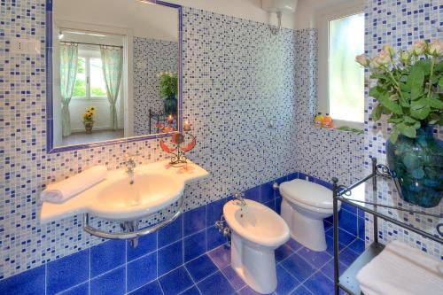 雷卡纳蒂港Villaggio Turistico Internazionale的蓝色瓷砖浴室设有水槽和卫生间