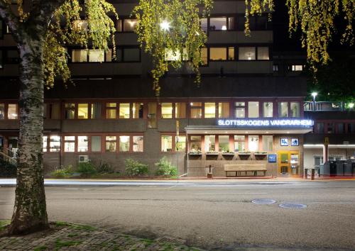 哥德堡Slottsskogens Hostel的一座晚上在前面有街道的建筑