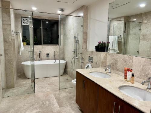 古尔冈luxury master bedroom with bathtub on golf course road的浴室配有2个盥洗盆、浴缸和淋浴。