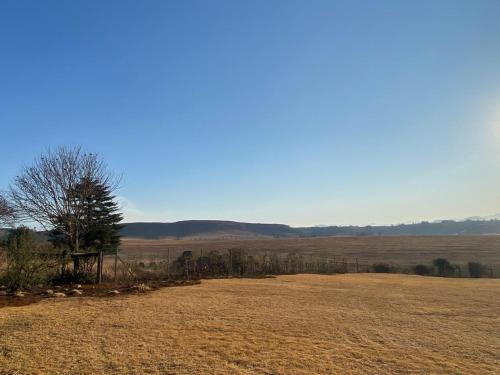 海姆维尔Sani Pass View Cottage的田野中间有树的田野