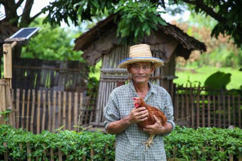 清迈Hang Tueng farm stay Chiang Mai แฮงตึง ฟาร์มสเตย์ เชียงใหม่的戴着帽子的男人,拿着鸡