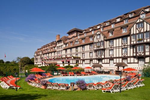 多维尔高尔夫巴里亚酒店的一座大型建筑,前面设有一个游泳池