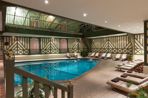 多维尔乐诺曼底巴里亚酒店的一座酒店游泳池,四周摆放着躺椅