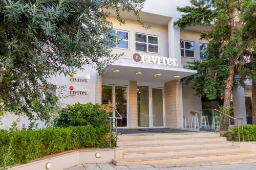 雅典Civitel Attik Rooms & Suites的前面有楼梯和树木的建筑