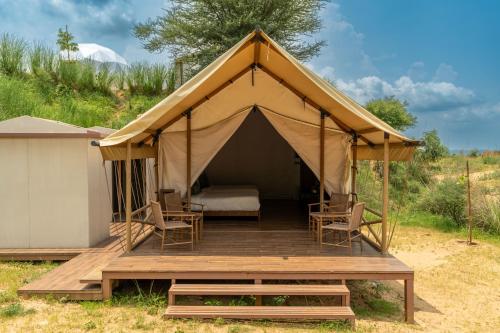 UdāsarTeela- The Glamping Resort, Jaipur的一个带椅子的帐篷和木甲板上的一张床