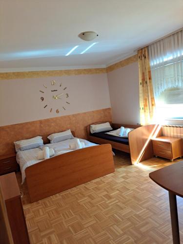 BišGostišče motel siva čaplja的一间卧室设有两张床,墙上挂着一个时钟。