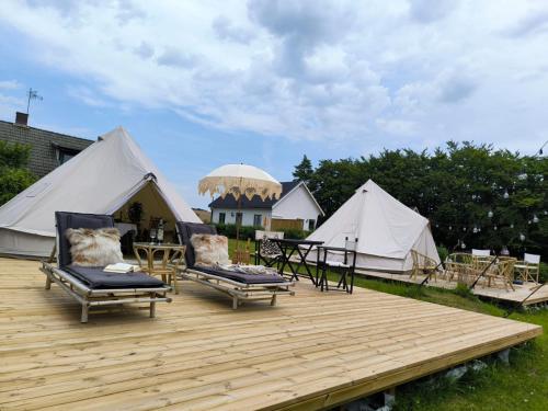 斯塔德Luxury Tent with Restroom and shower, close to the Beach的木制甲板上一组配有桌椅的帐篷