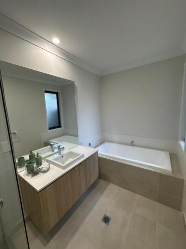 Narellan4 bedrooms beautiful home的浴室配有盥洗盆和浴缸。