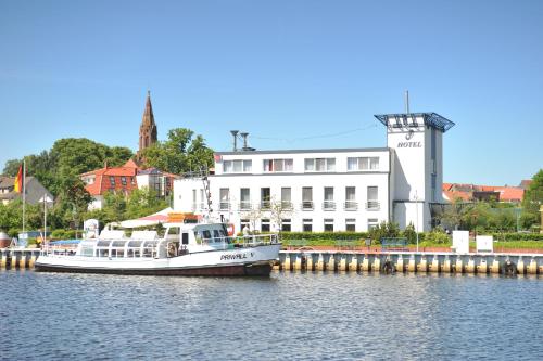 乌埃克尔明德波曼亚特哈芬酒店的船停靠在水中,靠近一座建筑