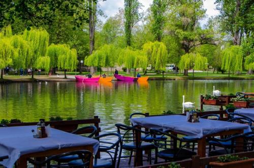 波格拉德茨Progradec, Lake Ohrid, Albania的两把桌子和椅子,位于带船的池塘前