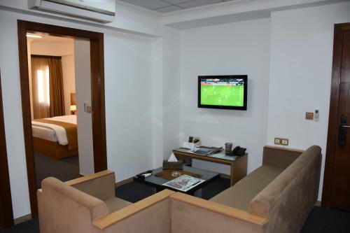 埃尔比勒Hayali Suites Hotel的客厅配有沙发和墙上的电视