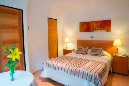圣地亚哥圣地亚哥蒙特卡洛酒店的一间卧室,配有一张床和一个花瓶,桌子上放着鲜花