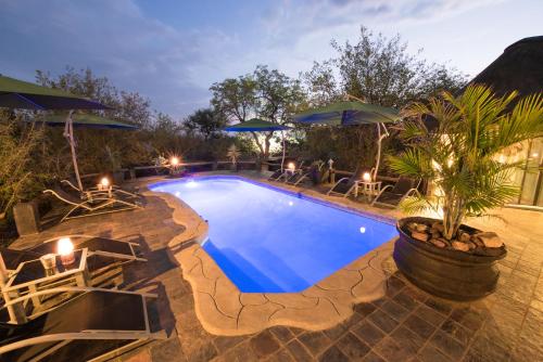 侯斯普瑞特非洲岩旅舍的度假村内带椅子和遮阳伞的游泳池