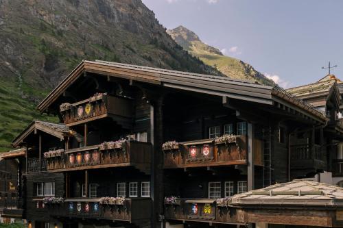 采尔马特SCHLOSS Zermatt - Active & CBD Spa Hotel的一座带花箱和阳台的建筑,位于山前