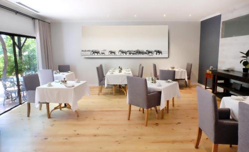 斯泰伦博斯Vine Guesthouse的一间用餐室,配有白色的桌椅和钢琴