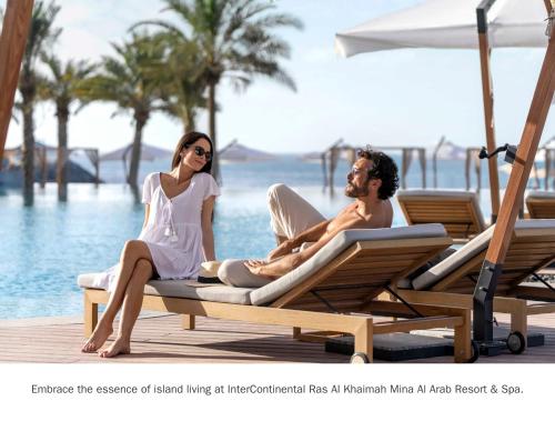 拉斯阿尔卡麦InterContinental Ras Al Khaimah Mina Al Arab Resort & Spa, an IHG Hotel的坐在水边躺椅上的男人和女人