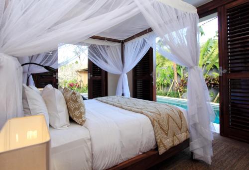 塞米亚克Villa Suar Drupadi的一间卧室配有一张带天蓬和游泳池的床