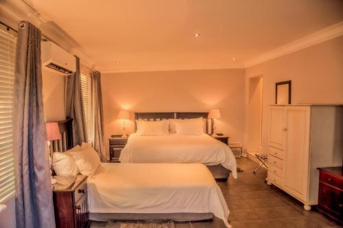 莱迪史密斯Nauntons Guest House & Wedding Venue的一间卧室配有两张带白色床单的床
