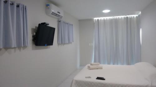 圣米格尔-杜戈斯托苏Pousada Brisa dos Ventos的白色的客房配有床和电视。