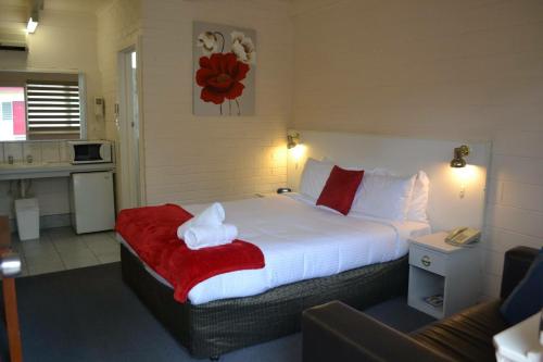 西摩金合欢树汽车旅馆的一间卧室配有一张带红色毯子的大床