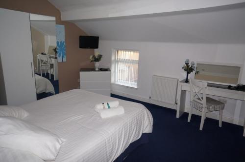 布莱克浦南海滩公寓的一间卧室配有一张床、一张书桌和一面镜子