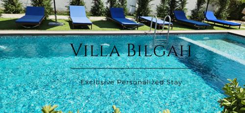 巴库Villa Bilgah Boutique Hotel的一个带蓝色椅子的游泳池,以及一个读出比亚利茨别墅的标志